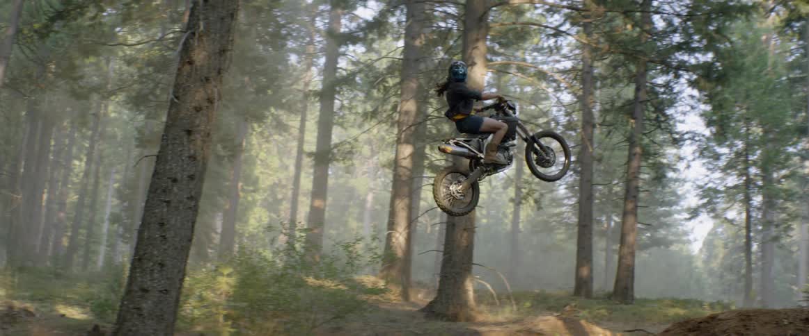 A motorcyclist goes over a jump in a forest