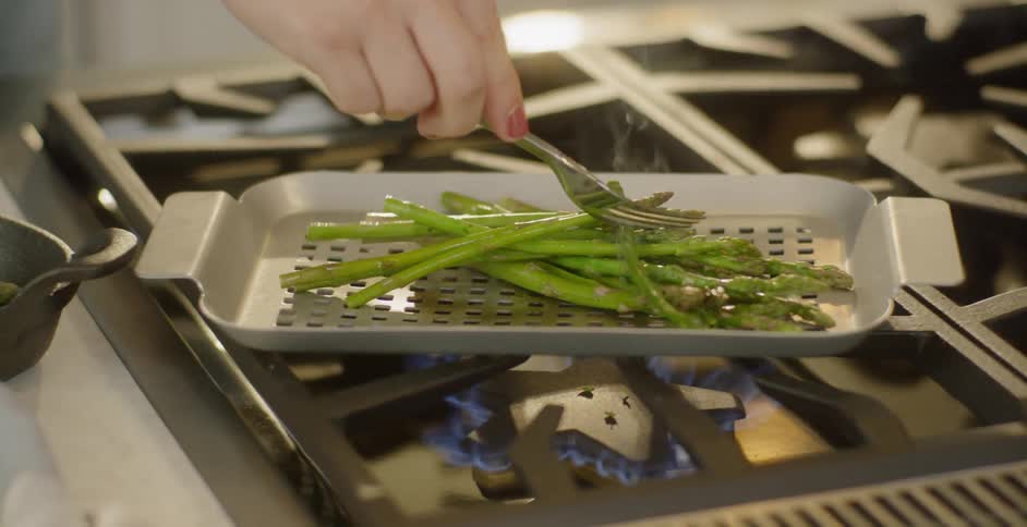 A woman cooks asparagus on the stove top