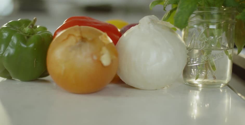 Vegetables sit on counter next to plant in mason jar