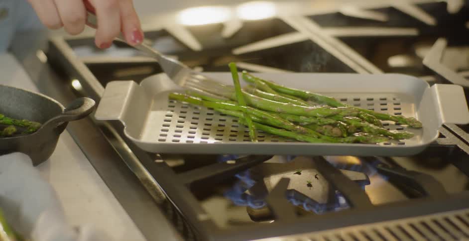 A woman cooks asparagus on the stove top