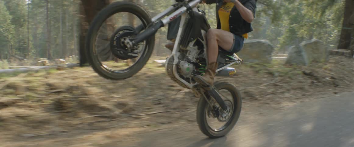 A woman rides a dirt bike on a forest trail