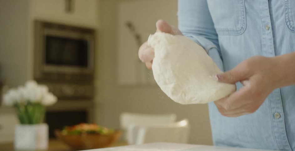 A woman kneads dough in a home kitchen