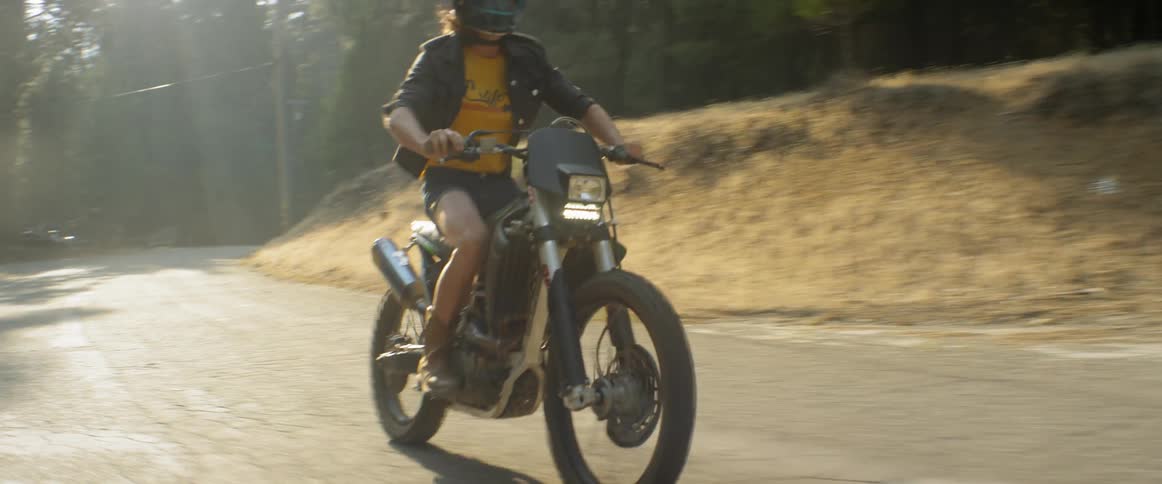 A motorcyclist pops a wheelie in a forest
