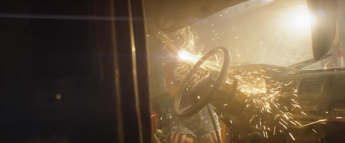 A woman welds the frame of a car