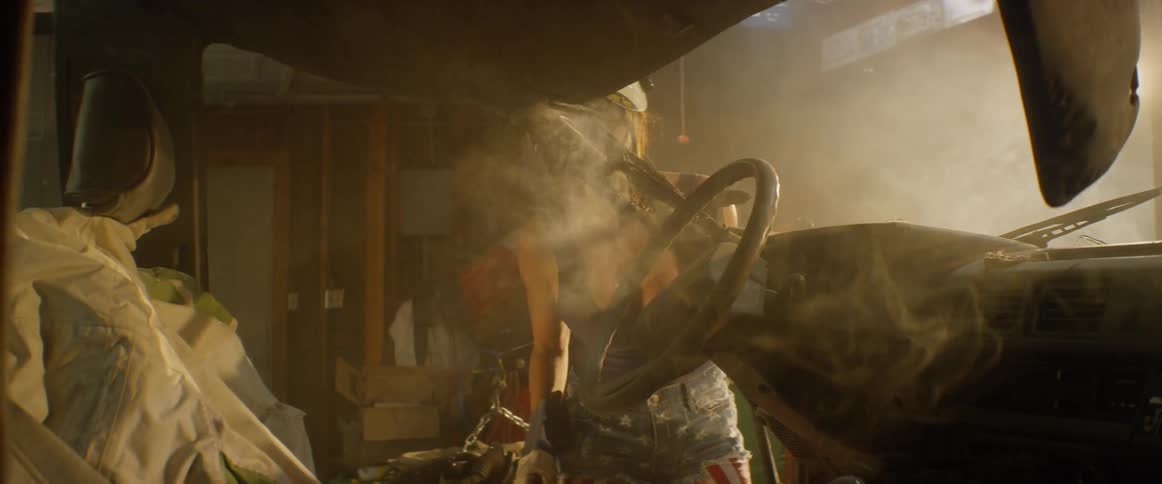 A woman welds a car in a garage