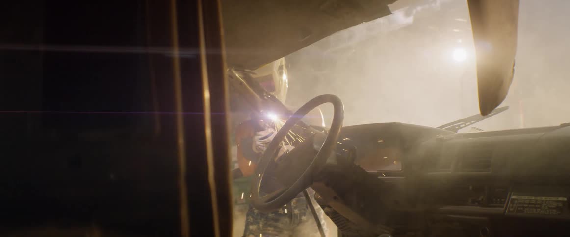 A woman welds a car in a garage
