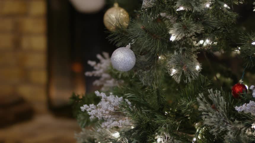 A fire burns in a fireplace near a christmas tree