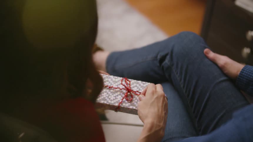 A person hands a gift box to someone sitting beside them