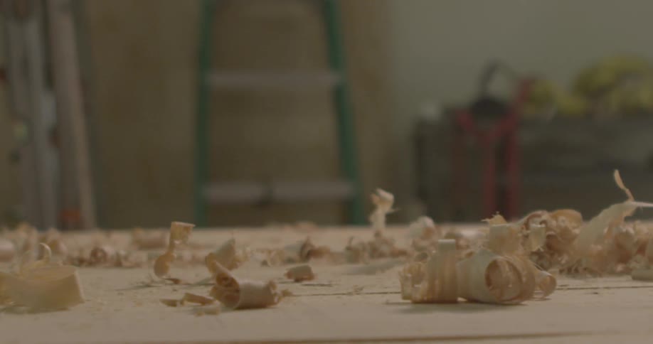 A person with a tool shaving wood