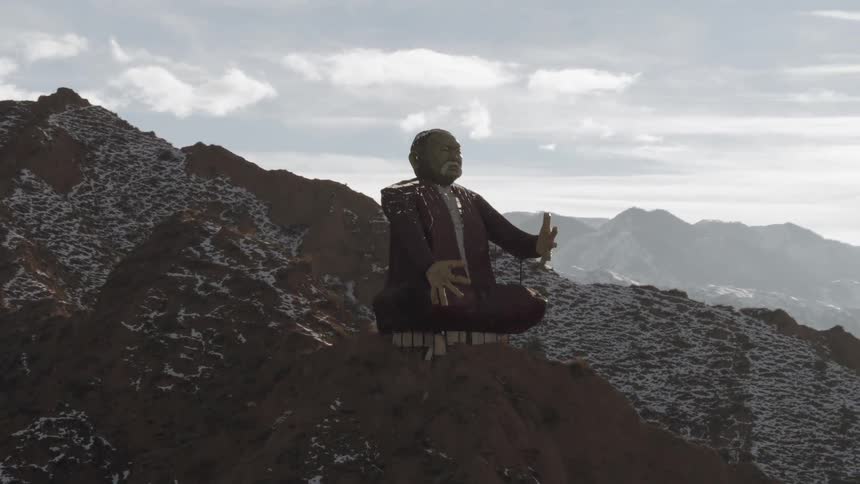 A statue sits atop a tall mountain