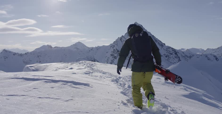A skier carries his skis up a mountain