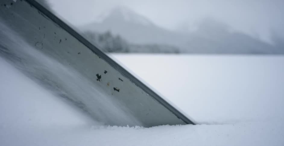 A man saws a hole in a frozen lake