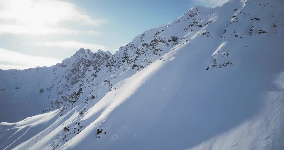 A person skis down a steep slope on a sunny day