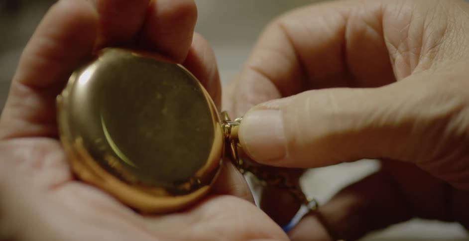 A person twists a dial on a pocket watch