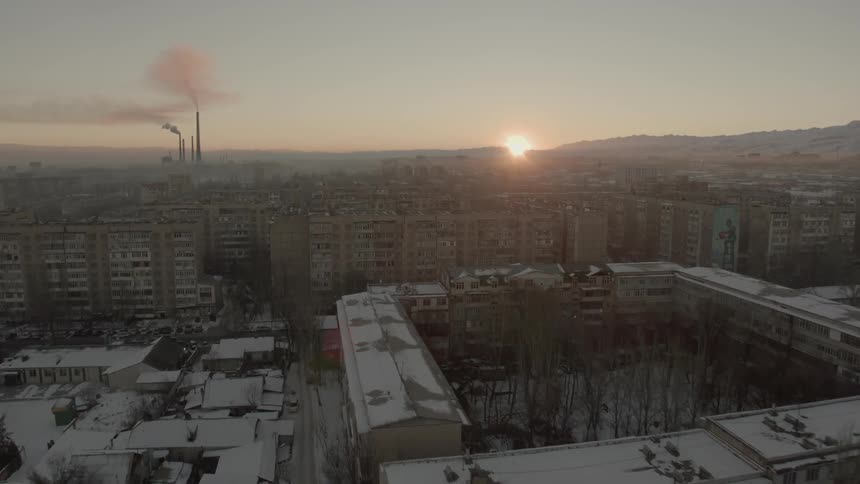 Sun setting behind mountains in the far distance of a large city