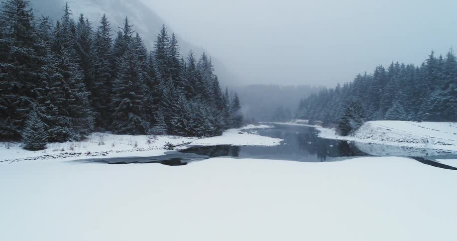 Snow falls on a partially snow and ice covered lake