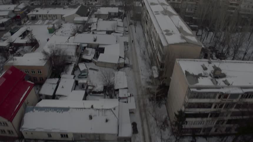 Snow covers buildings in a city at sunset
