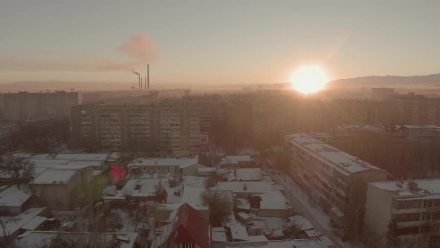 The sun is sitting on a snow covered city