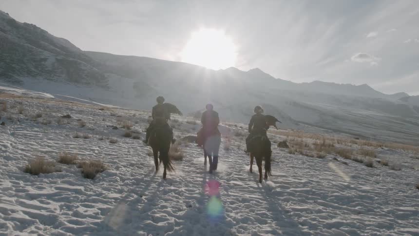 People ride horses in snowy mountains