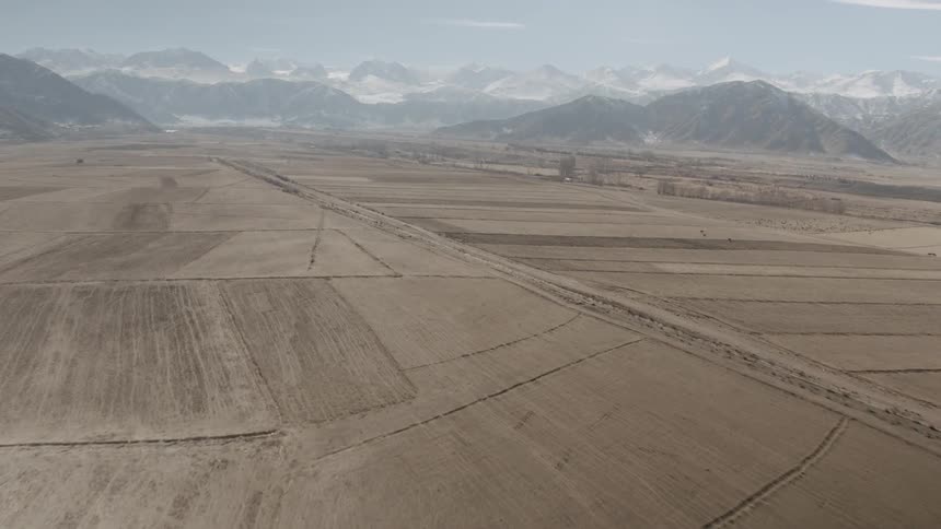 The long crop fields are barren before the mountain