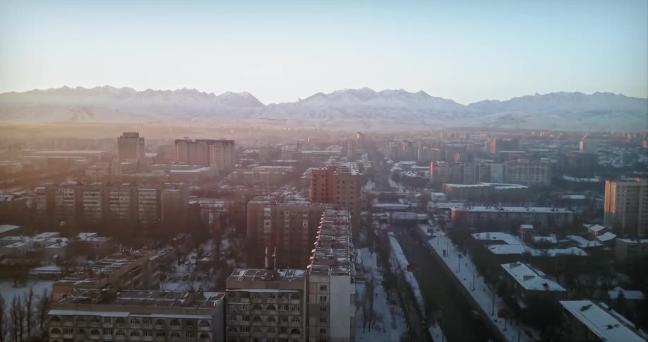 A haze is settling over a city near a river on a winter morning