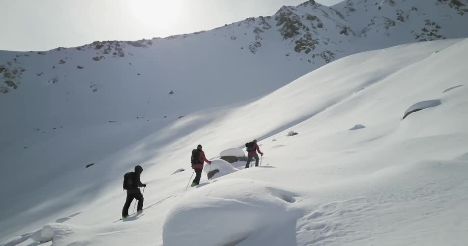 Hikers climb up a snowy mountainside
