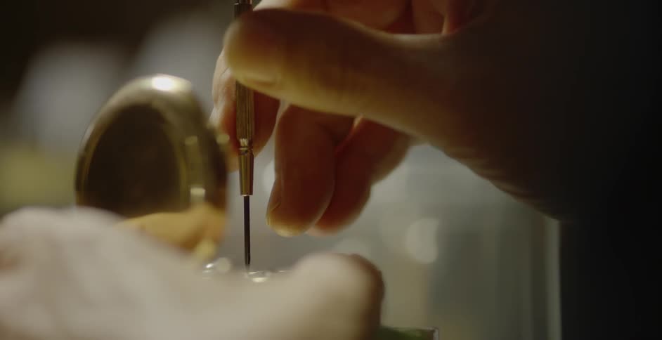 Person using fine tool to work on a pocket watch