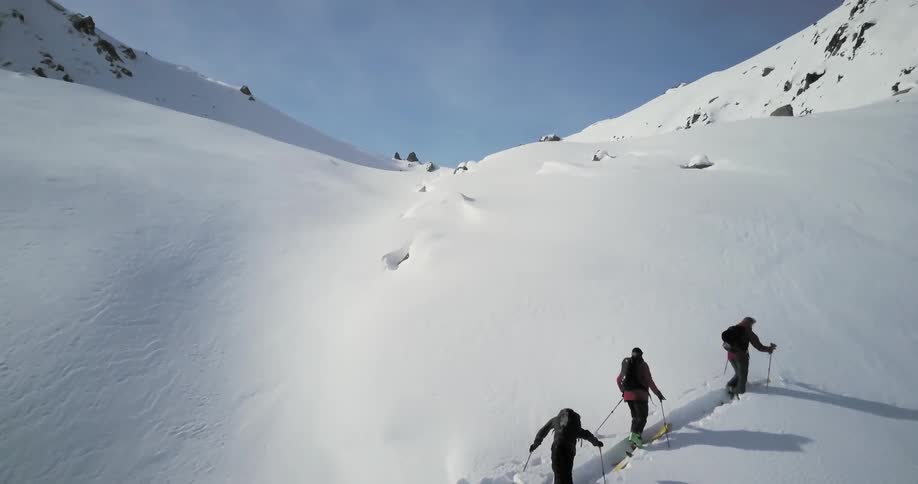The people are hiking up the snow covered mountain on a sunny day