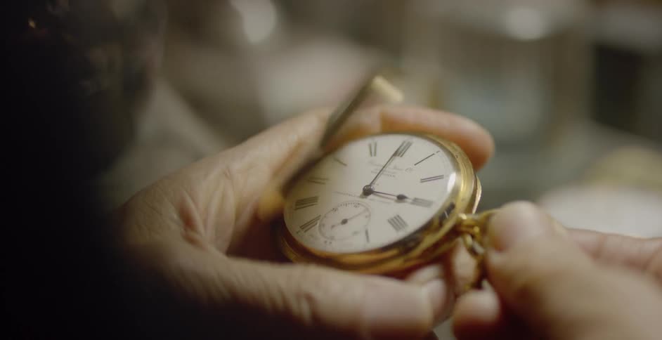 Elderly person examines gold pocket watch