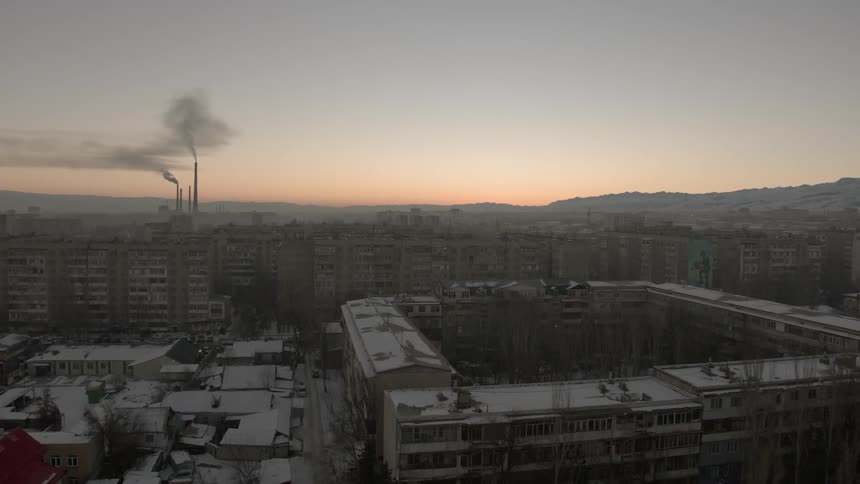 A frozen city with smoke stacks in the distance