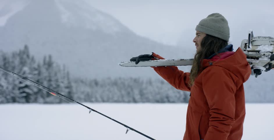 A man walks in the snowy wilderness with a fishing pole