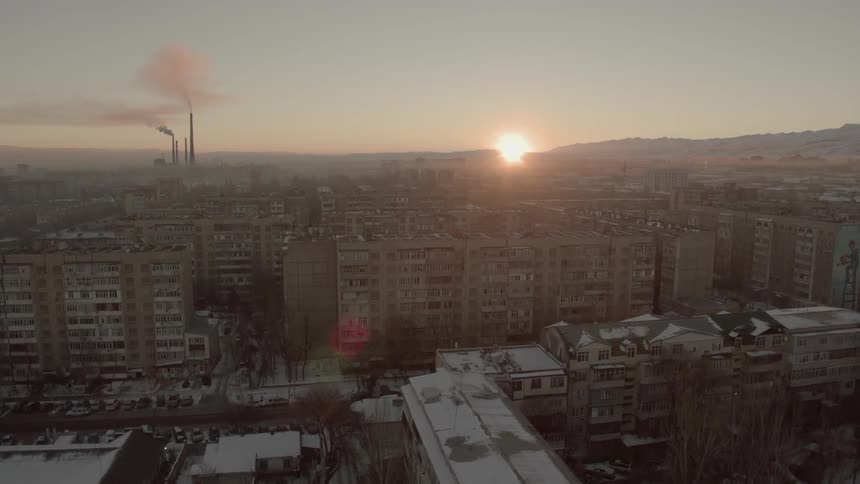 The sun sets over a snowy city