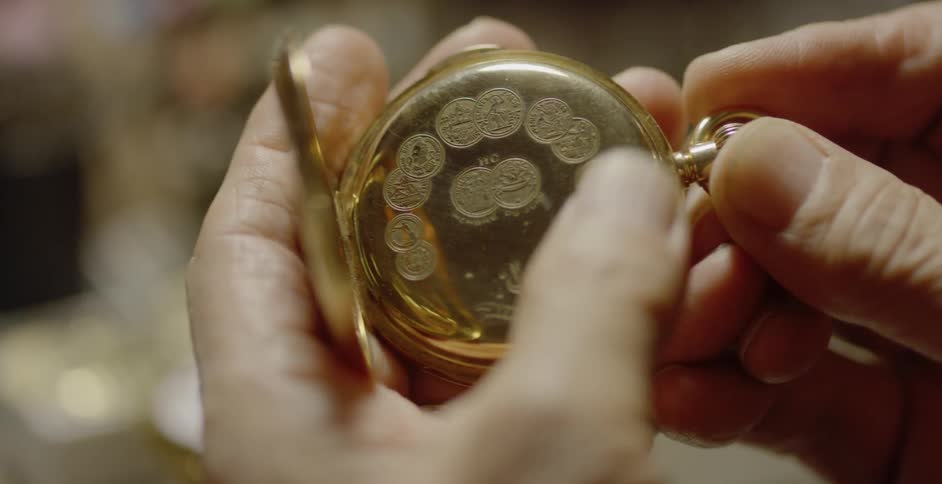 A man is closing up a pocket watch he is holding in his hands