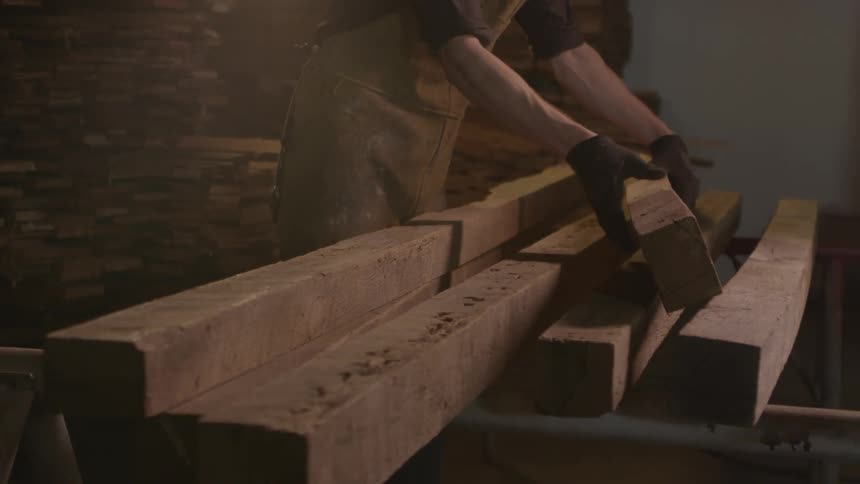 A worker removes a wood beam from a pile