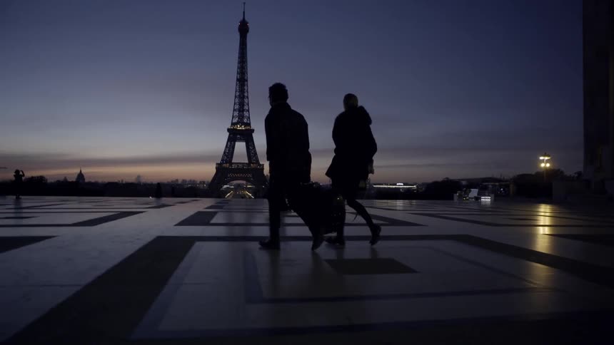 People walk past the eiffel tower at sunset