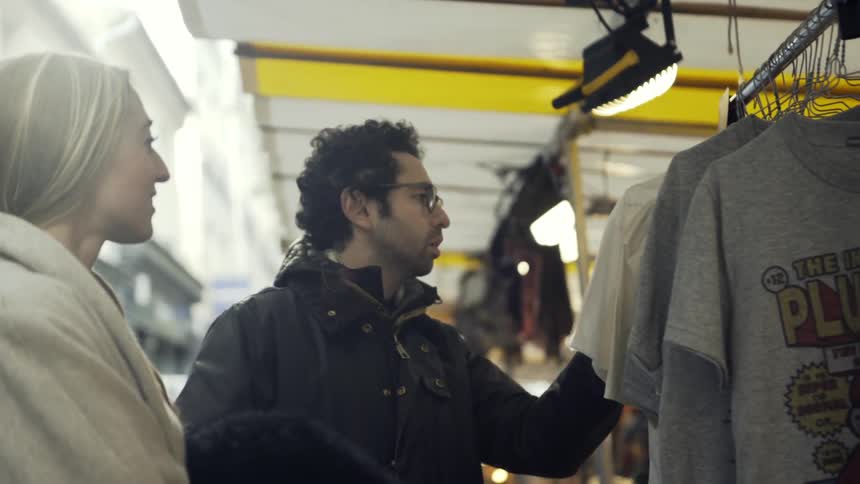 A man and woman browse through shirts in a shop