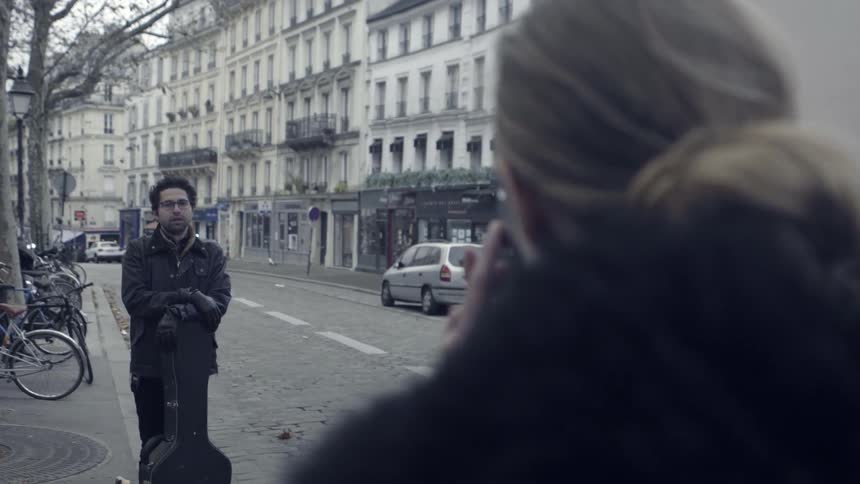 A woman photographs a man on the side of a city road