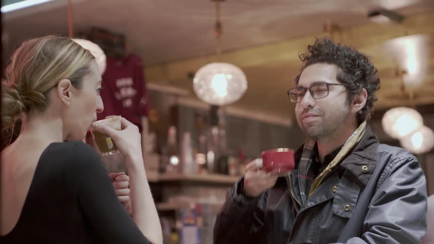 A man and woman drink and talk inside a coffee shop