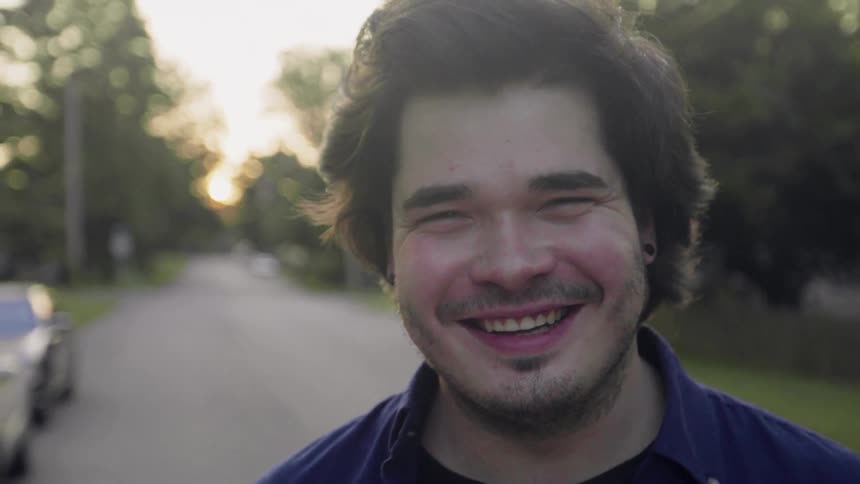 A man is standing in the middle of the street smiling at the camera
