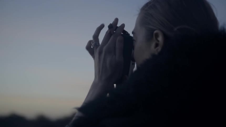 A woman is taking pictures of the eiffel tower at dusk