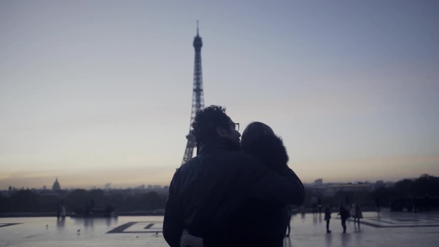 A man and woman hug in front of the eiffel tower