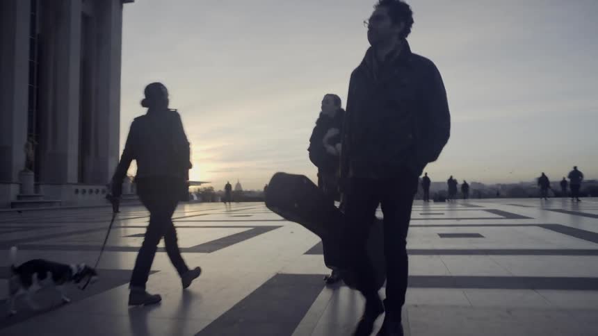 Pedestrians walk near the eiffel tower at sunset