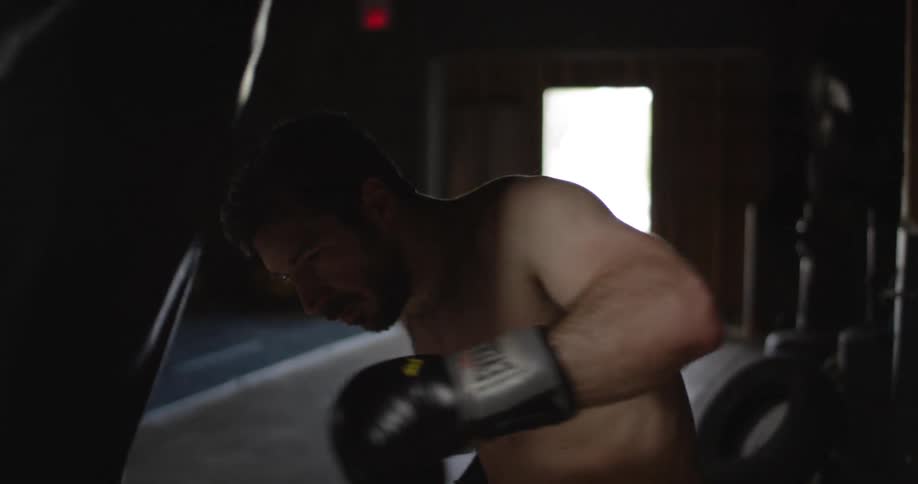 A boxer trains on a heavy bag in a gym