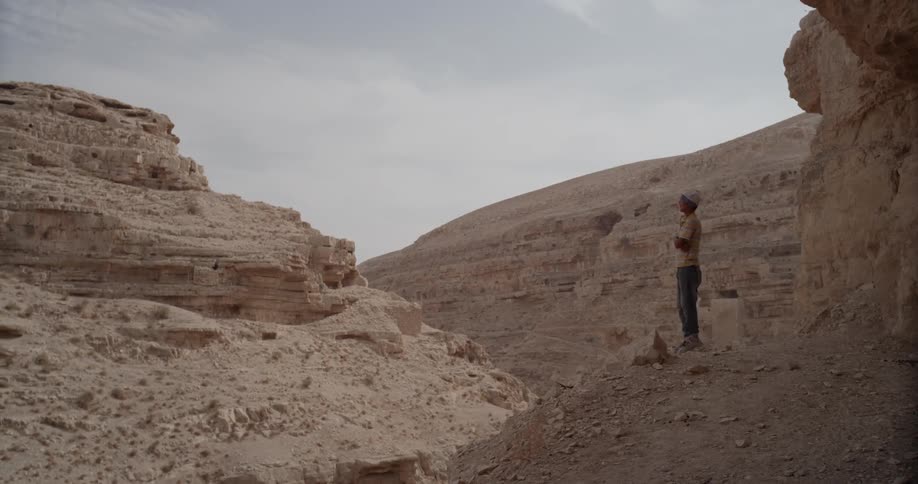 A man stands on a ledge inside a canyon
