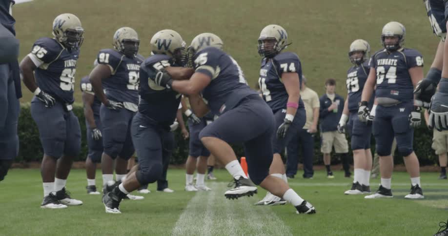 A football team practices in full pads and uniforms on the field