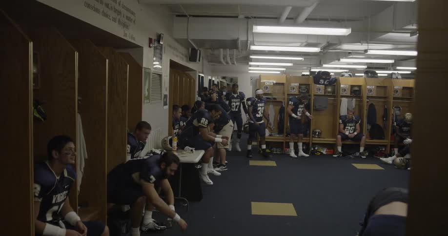 The football players are sitting around the locker room preparing