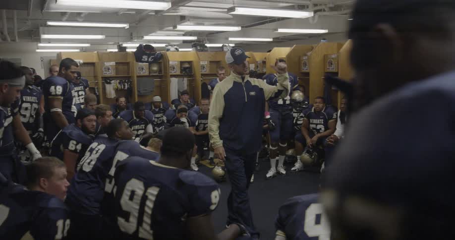 Coach talks to football players in locker room
