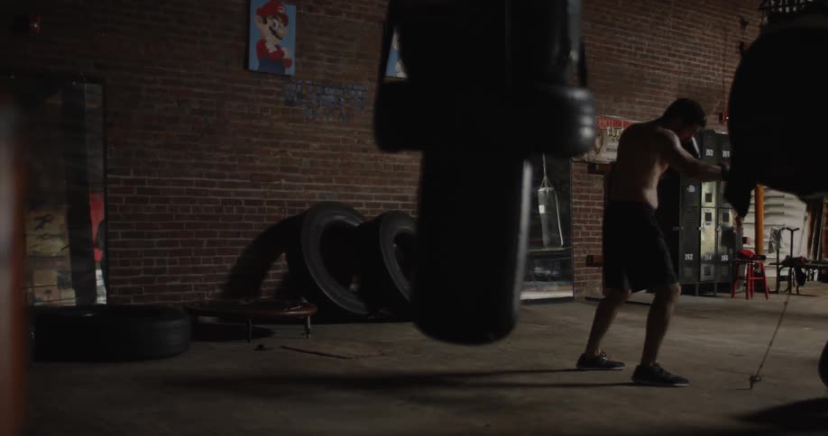 A boxer is punching a speed bag in a gym during the day