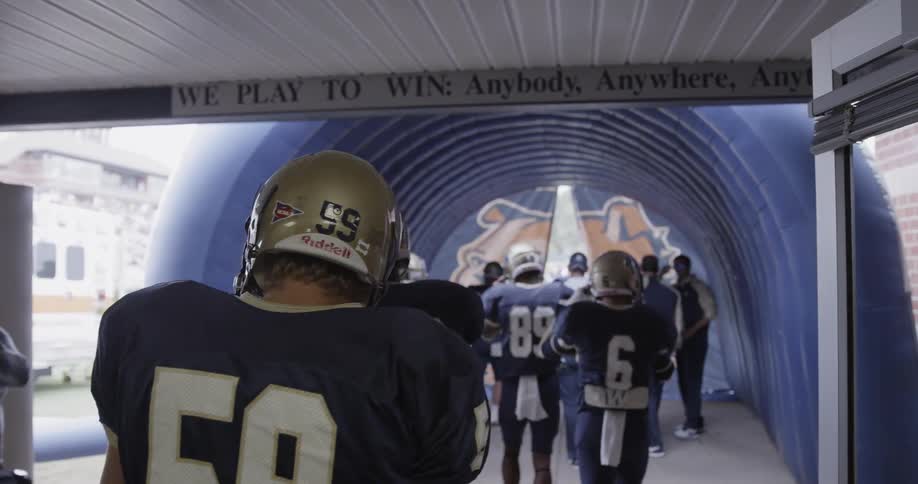 The football players walk out of the exit towards the field