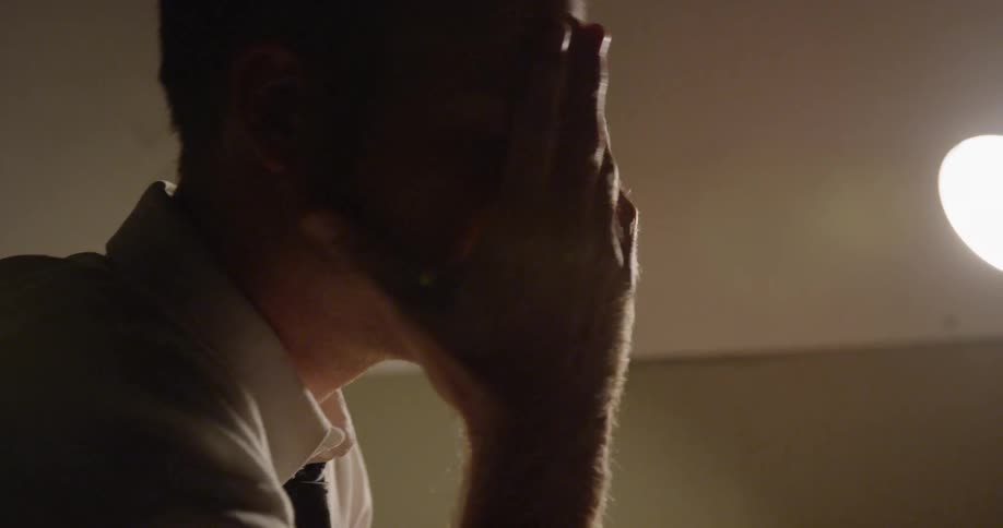 A man rubs his face while working at a desk
